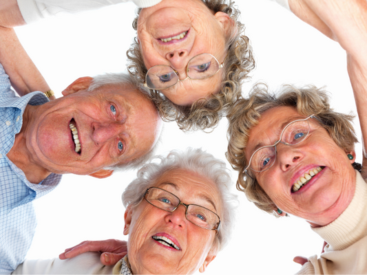 Vier ältere Menschen schauen lächelnd aus einer Vogelperspektive in die Kamera – symbolisiert Gemeinschaft und unterschiedliche Pflegebedürfnisse von Pflegegrad 1 bis 5.